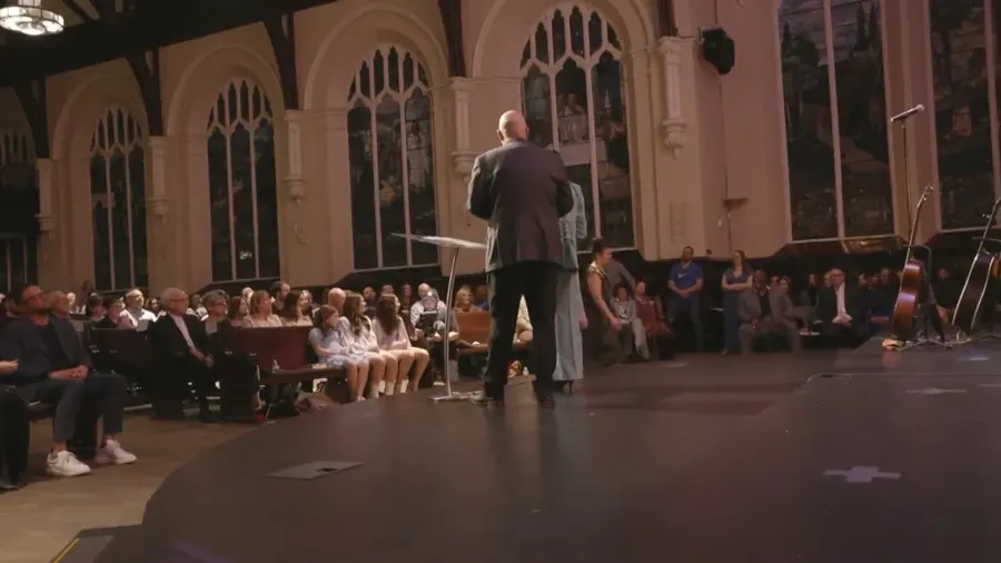 A handheld shot from the stage behind a speaker, looking out at the front rows