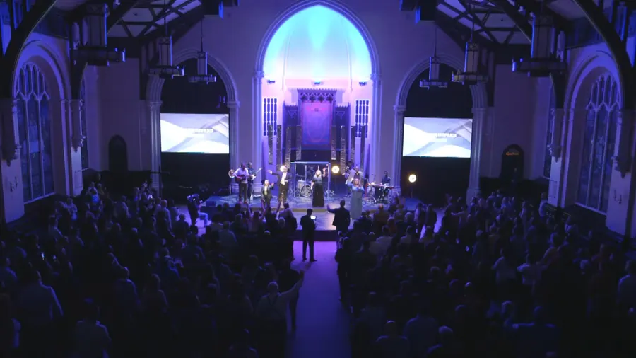 The high wide from the back of the sanctuary under blue light during the closing worship