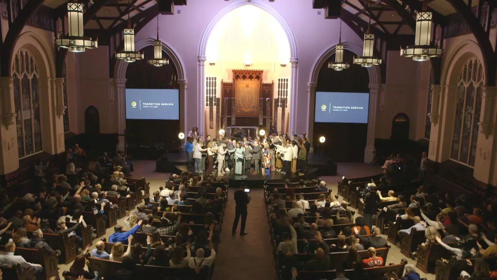 The high wide from the back of the sanctuary with the stage full of people and the congregation standing