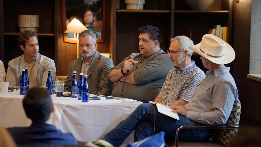 A panelist talking with a microphone while the people beside him listen