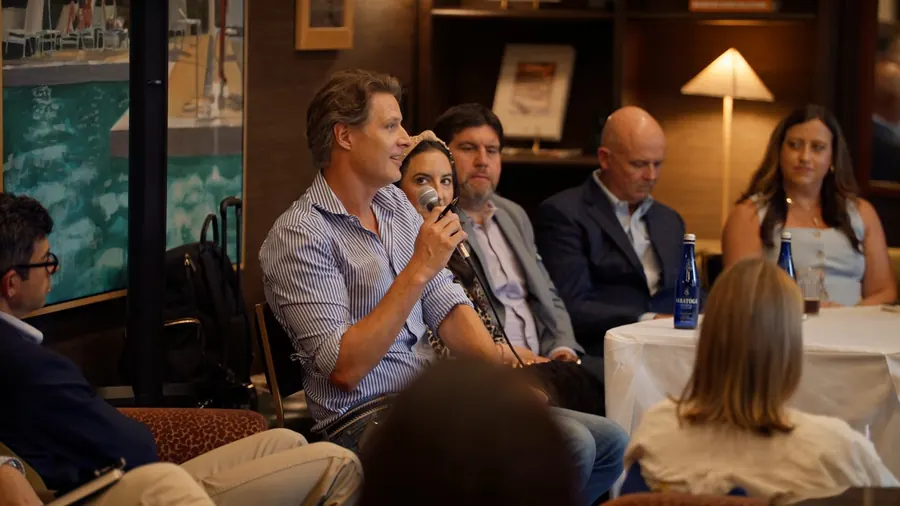 A close shot of a panelist in a striped shirt speaking into a microphone