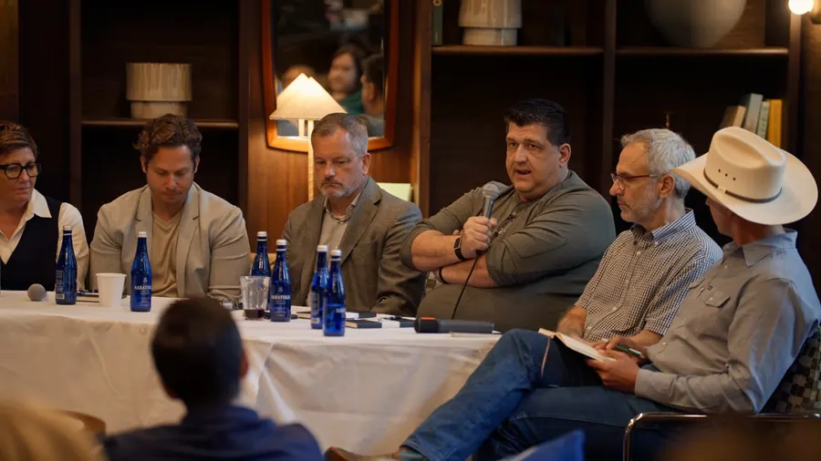 Four panelists at the right table, one with a microphone