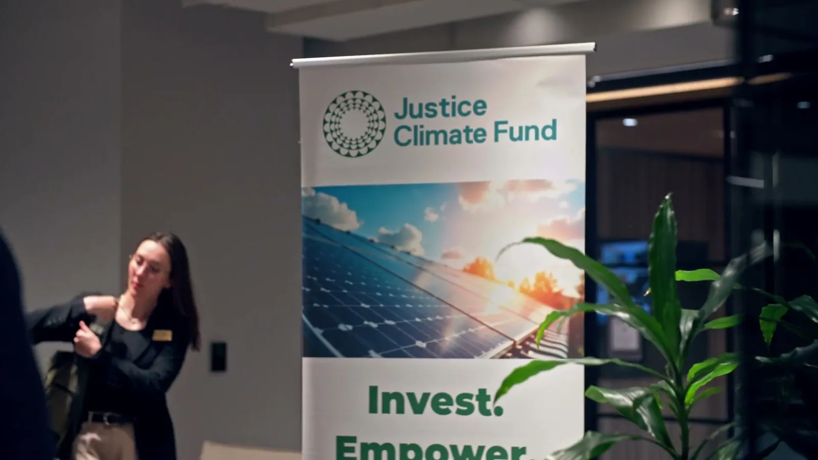 A woman at the check-in area beside a Justice Climate Fund banner with solar panels on it