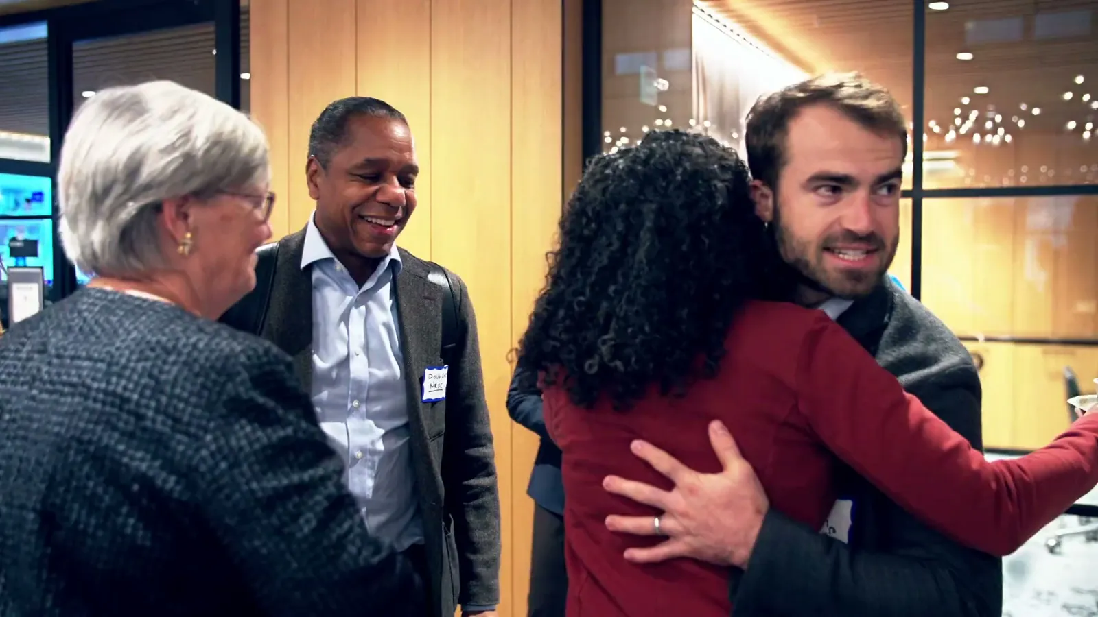 Two guests hugging while two others stand beside them smiling