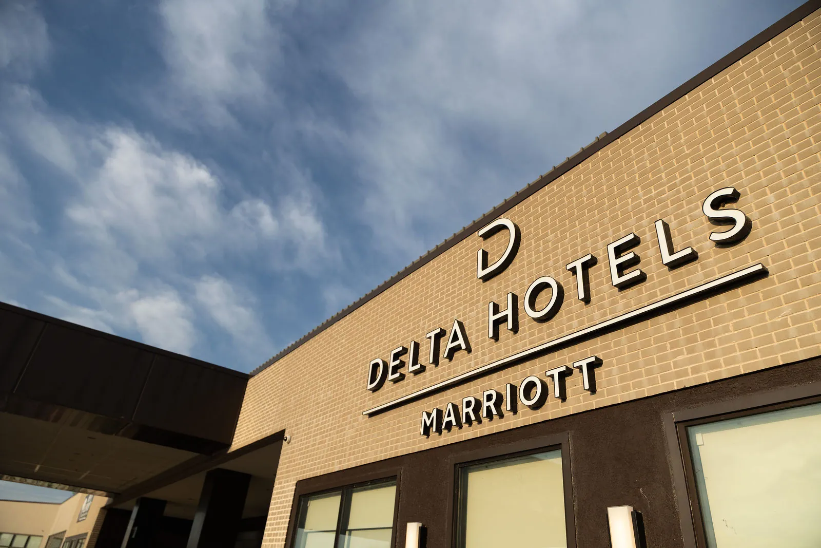 The Delta Hotels by Marriott sign on the building against a blue sky