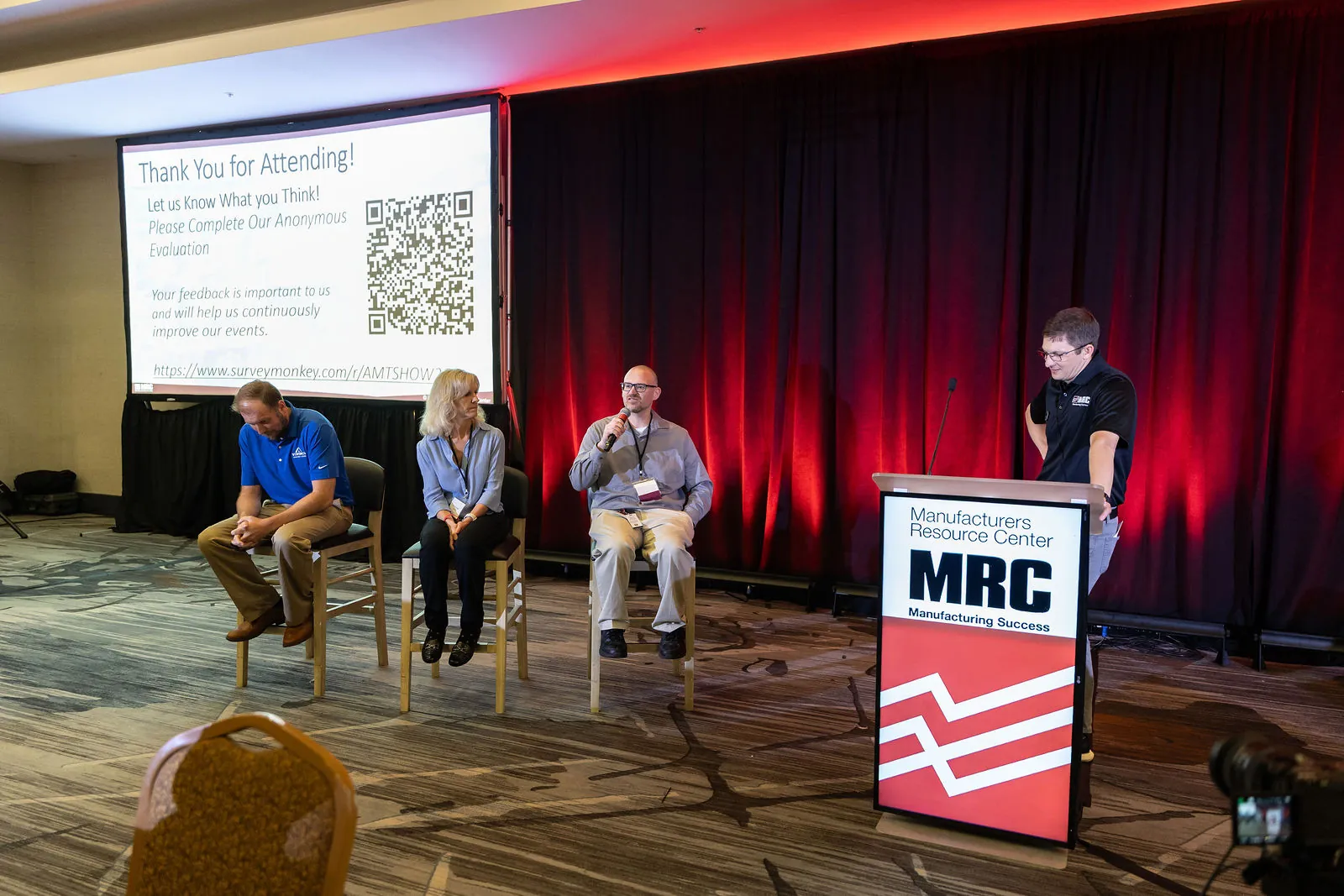 The speaker panel seated on stage with the moderator at the podium