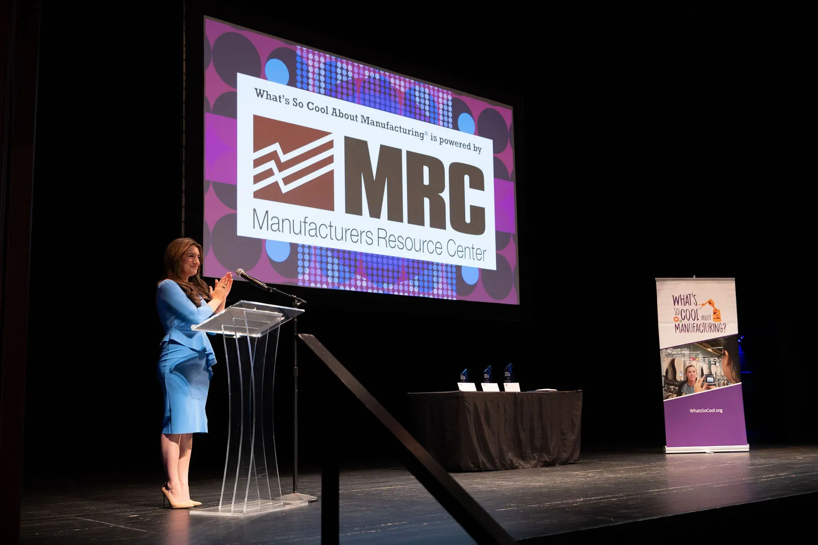 The Manufacturers Resource Center logo on the big screen above the stage, with Brittany Stephens at the podium