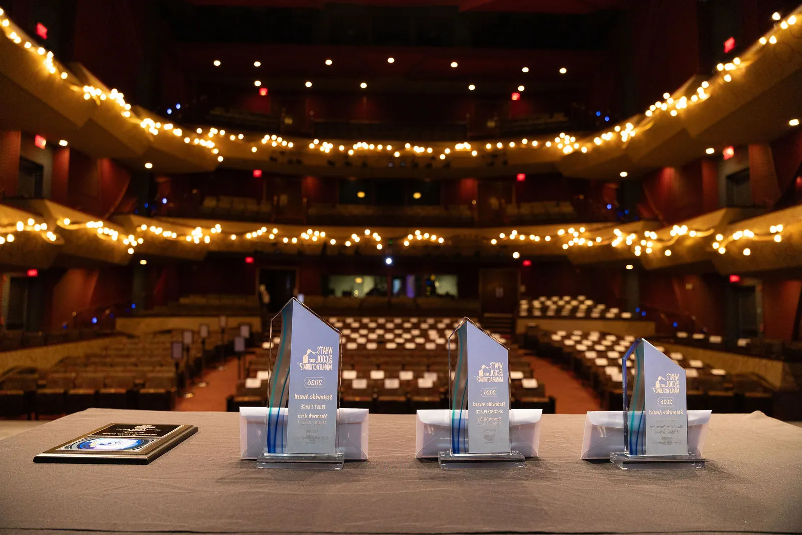 Three statewide trophies on the stage with the empty Whitaker Center theater and its string-lit balconies behind them