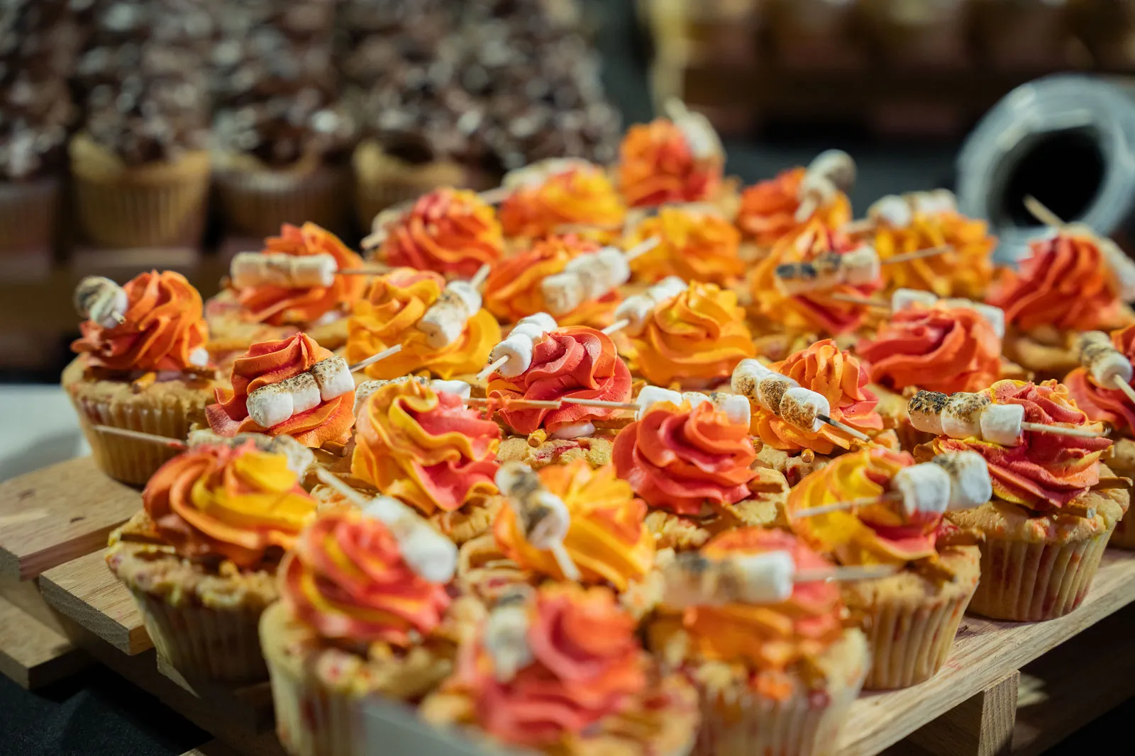 Close-up of orange and red frosted cupcakes on a wooden display