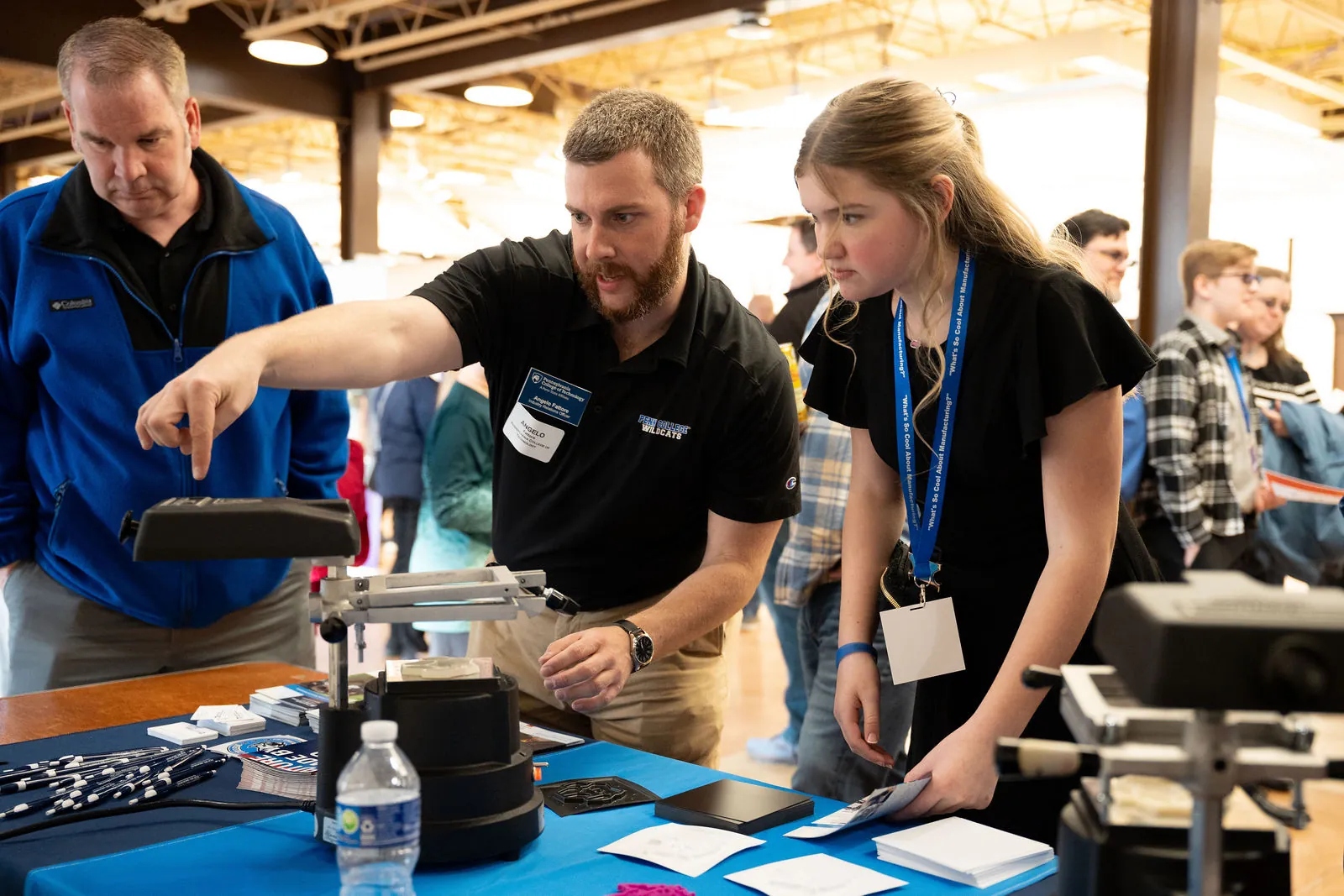 A manufacturer showing students and a parent a hands-on demo at his table