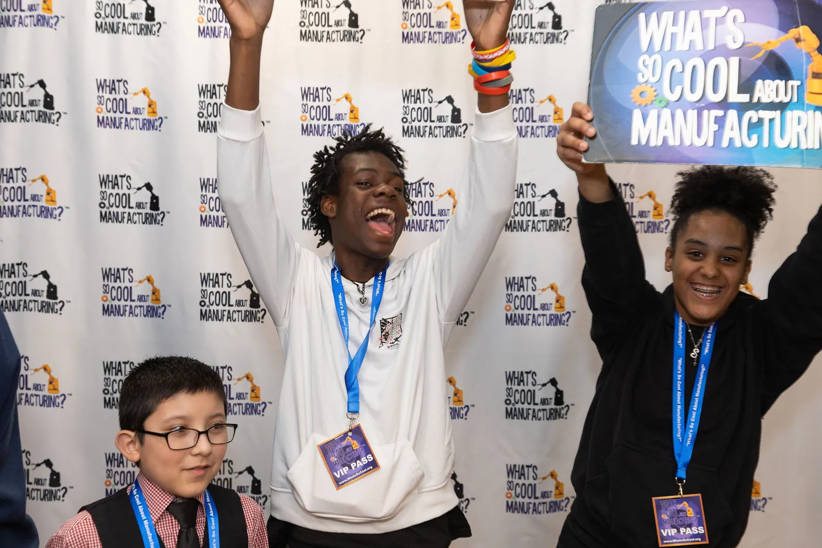 A student with both arms in the air celebrating at the step and repeat