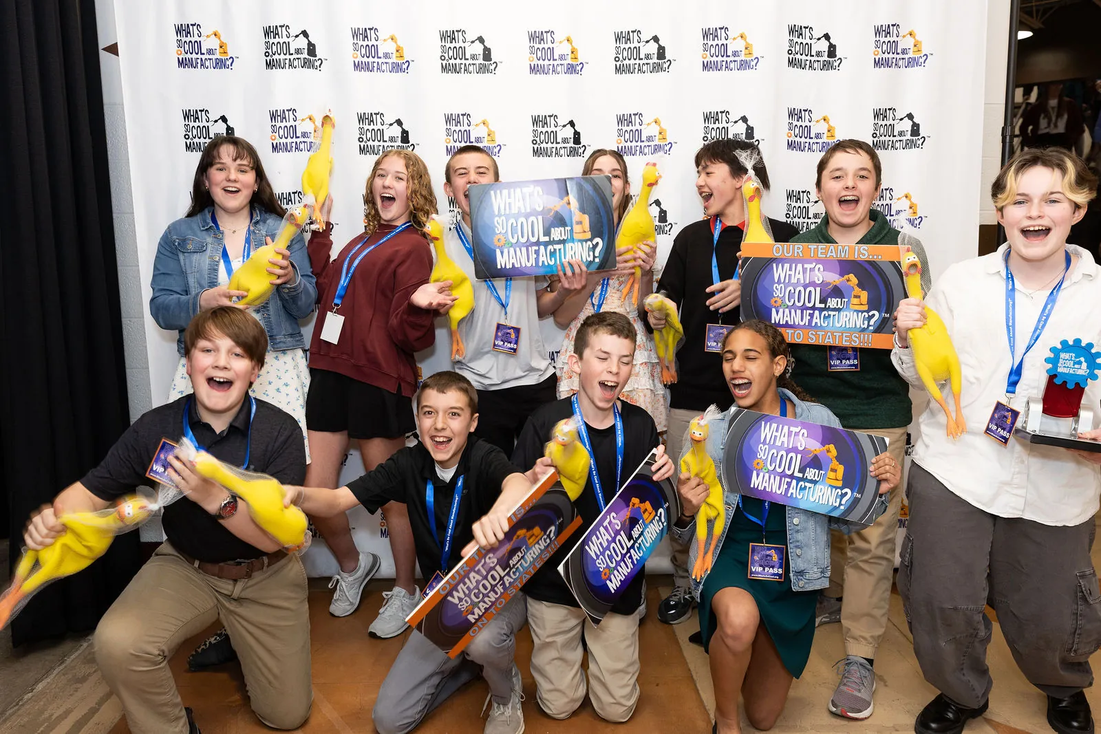 A winning team posing with rubber chickens, signs and a trophy at the step and repeat
